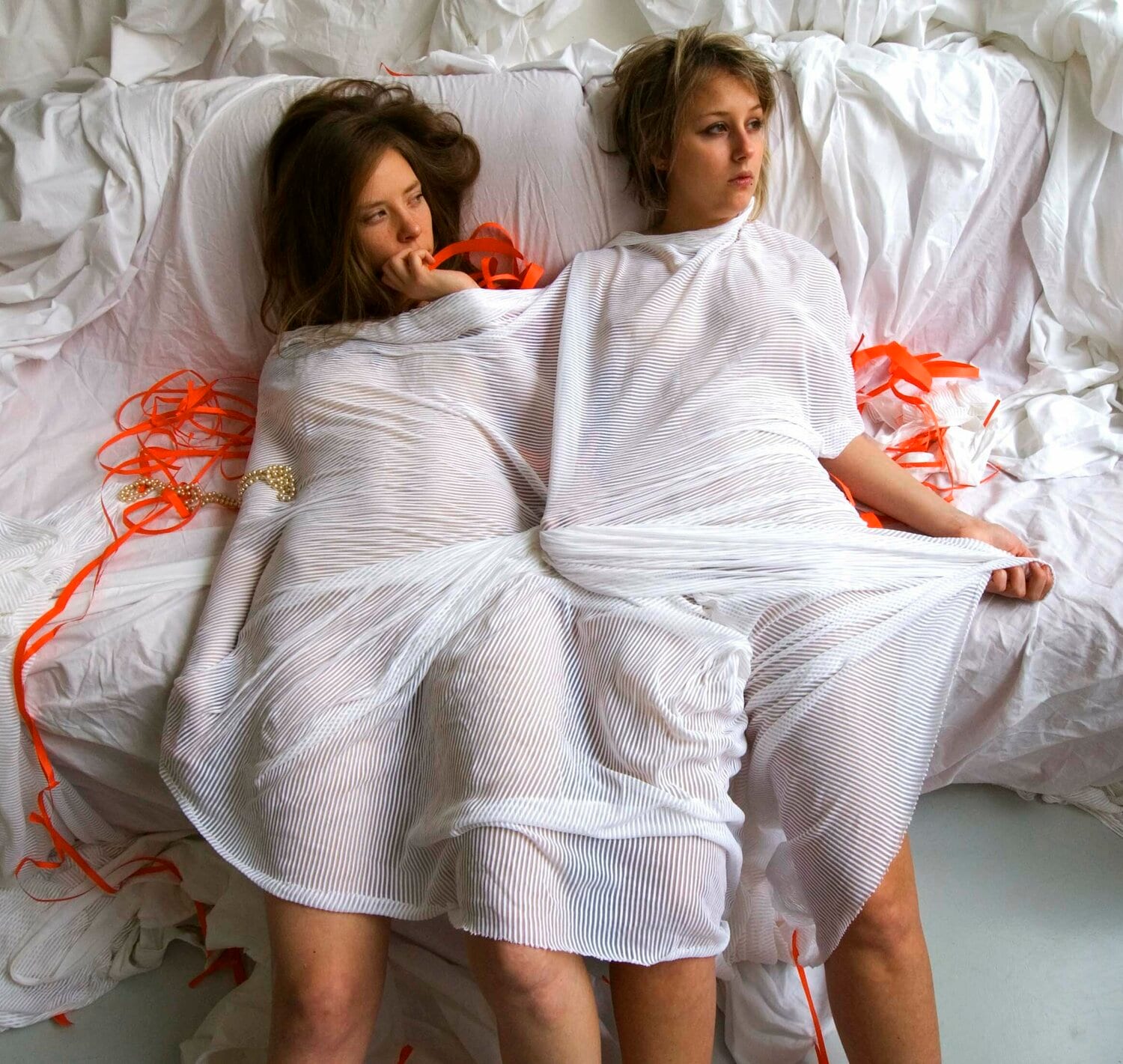 Two women wrapped in white sheets with a red thread. afactum, 2010, Digital print on metal, Alu-Dibond, 50 x 52 cm